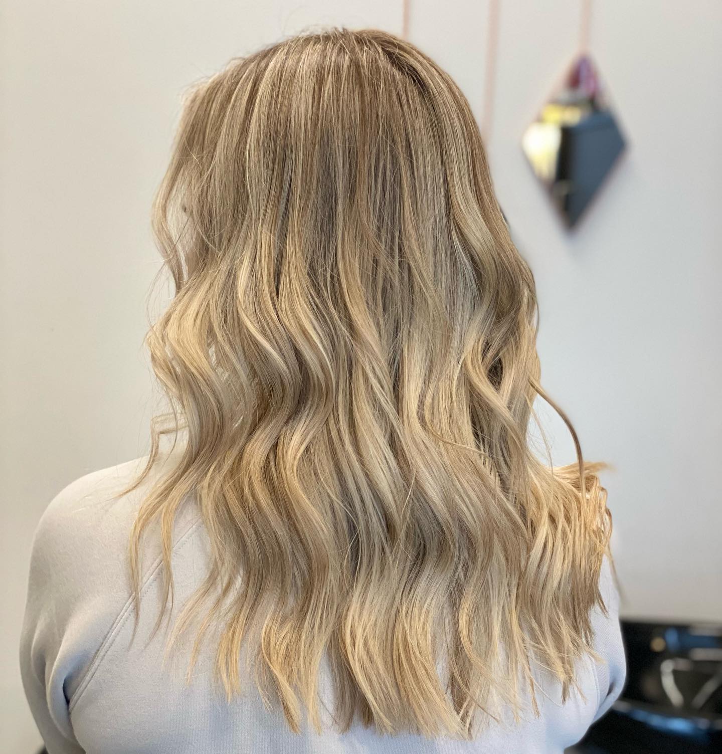 Shoulder-length blonde waves with soft dimensional tones.