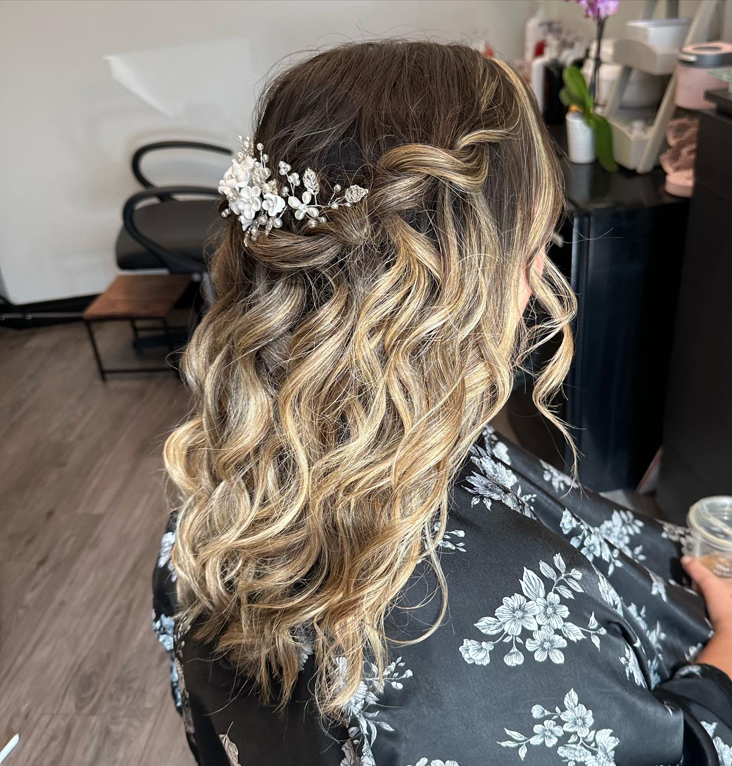 Blonde waves styled half up with a white floral hairpiece.